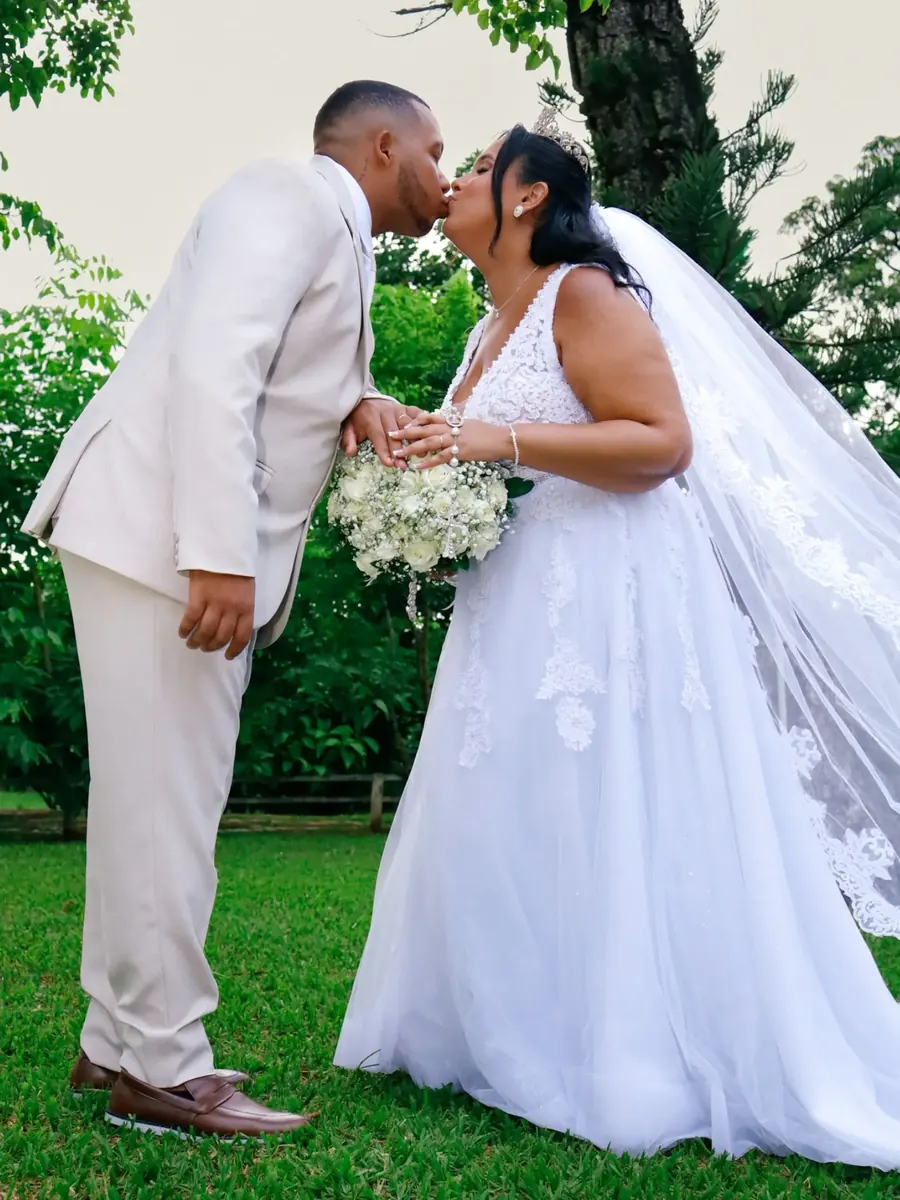 Noivos se beijando no jardim, noiva com véu longo